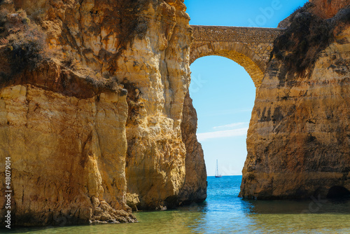 Detailed View of arched bridge with sailboat in Students Beach in Lagos, Algarve, Portugal © Dartagnan1980