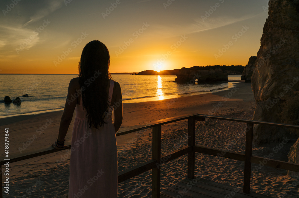Woman at back in a runway enjoying the sunset in the beach in Algarve, Portugal