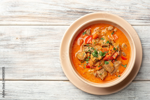 Traditional hungarian paprikash with turkey, bell pepper, carrot, onion, paprika and sour cream in bowl on rustic wooden background