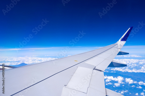 Photo of airplane wing with clouds background  horizon line and clear blue sky