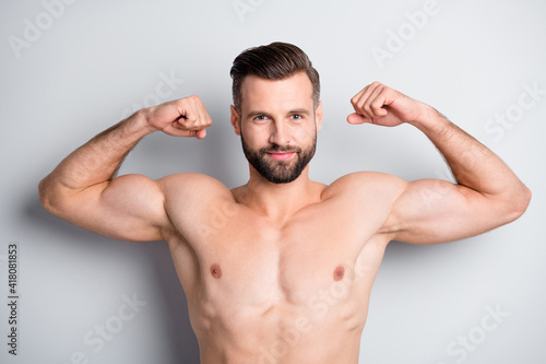 Close-up portrait of attractive cheerful guy demonstrating muscles protein isolated over light grey color background