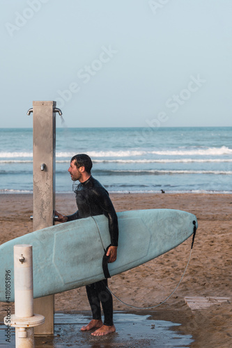 Fotografie Male wearing a neoprene suit holding a surf board