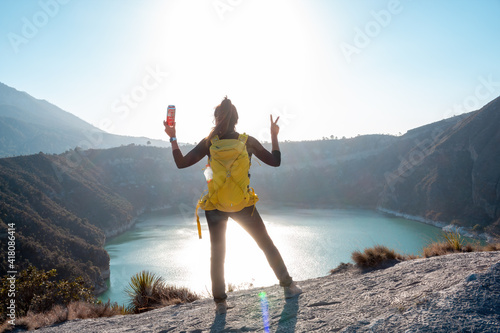 Back view of an elegant brunette female enjoying the view of the lake surrounded by hills