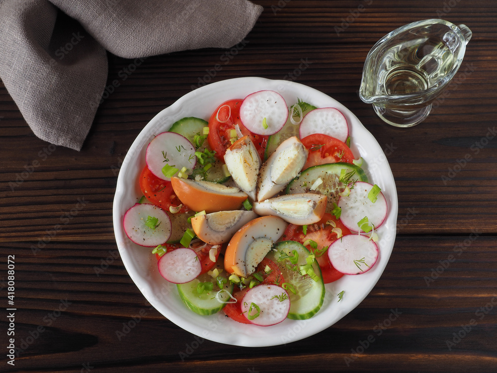 Slices of smoked egg, tomatoes, cucumber, radish with green onions and spices in a plate, olive oil on a dark wooden table, flat layout. Recipe for vitamin salad with chicken eggs Slices of smoked egg, tomatoes, cucumber, radish with green onions and spices in a plate, olive oil on a dark wooden table, flat layout. Recipe for vitamin salad with chicken eggs
