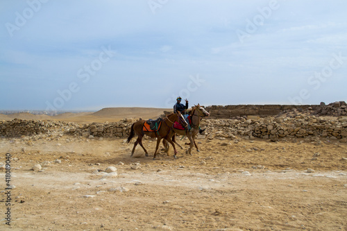 Cairo / Egypt - February 09 2021: A horseman riding in Giza Pyramids area. Horseback and camel riding are traditional rituals at the grounds of Giza Pyramids.