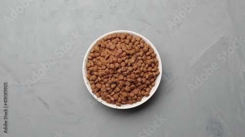 Dry cat food in a plate loop rotates. Top view.