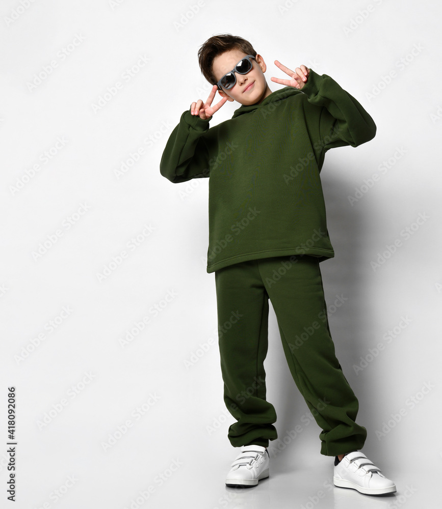 Active coolest boy in a tracksuit and white sneakers on a white background. The concept of sports and a healthy lifestyle for a modern child. Place for text. Active coolest boy in a tracksuit and white sneakers on a white background. The concept of sports and a healthy lifestyle for a modern child. Place for text.