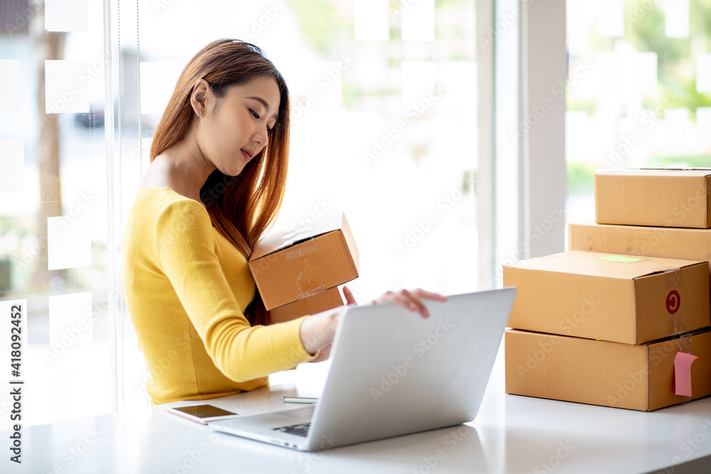 Person preparing online store orders for shipping using box and laptop Person preparing online store orders for shipping using box and laptop