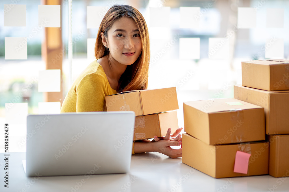 Person preparing online store orders for shipping using box and laptop Person preparing online store orders for shipping using box and laptop