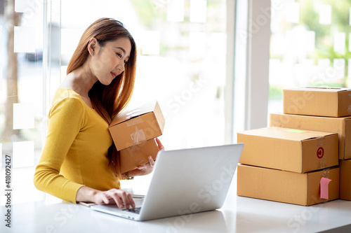 Person preparing online store orders for shipping using box and laptop