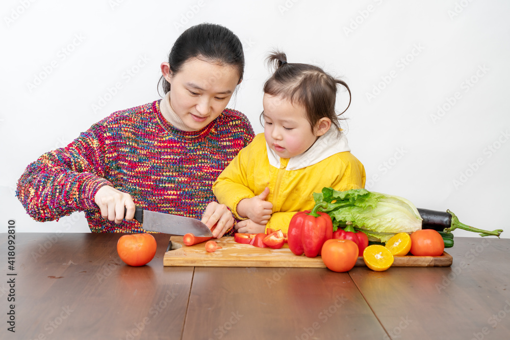 Fototapeta premium Mother and girl are tidying up vegetables in the kitchen