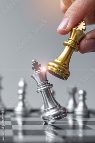 Close up of hands of a business man moving king golden chess to defeat  opponent the chess game is development analysis, strategy, and plan, the  management or leadership concept. 22804709 Stock Photo