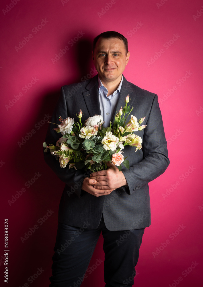 handsome businessman in a suit looks at the camera with a bouquet of flowers. handsome businessman in a suit looks at the camera with a bouquet of flowers.