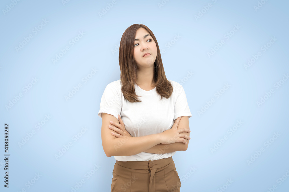 Portrait of an upset unsatisfied asian woman standing with arms folded and looking away isolated on blue background. with clipping paths. Portrait of an upset unsatisfied asian woman standing with arms folded and looking away isolated on blue background. with clipping paths.