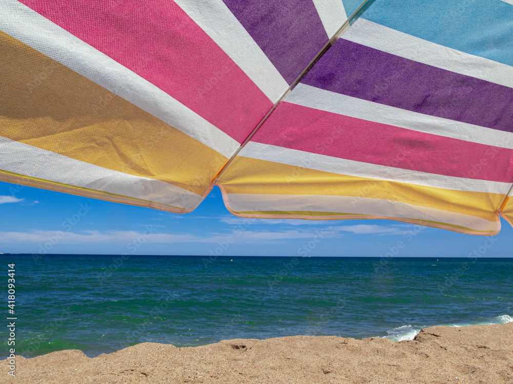 beach umbrella in the summer of spain with multi coloredin a blue sky
