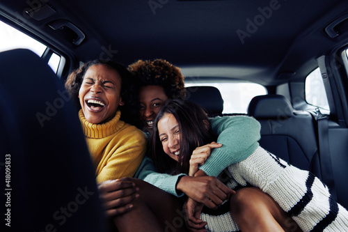 Group of diverse young female friends laughing in a car