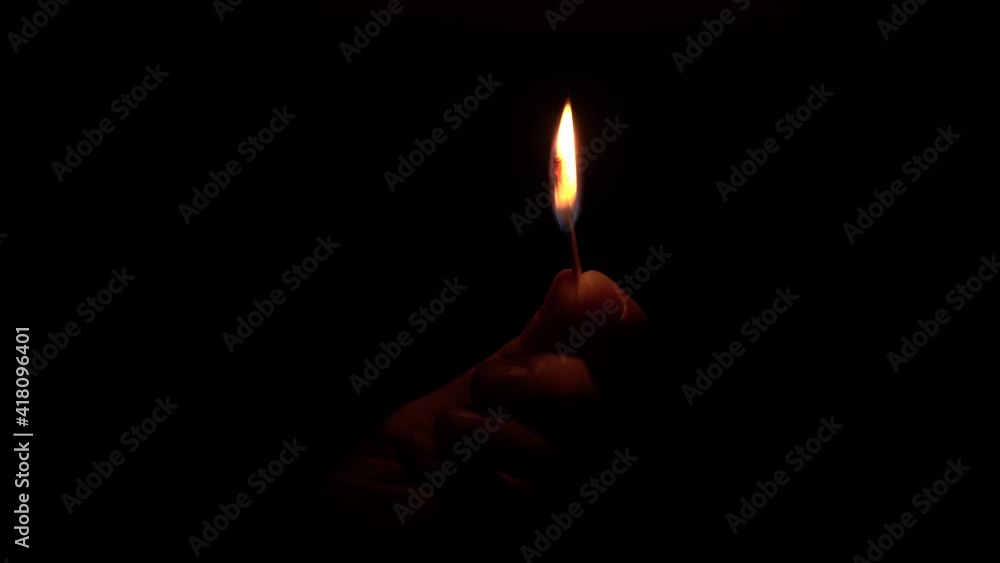 Hand holding a match flame burning in a dark room. Hand holding a match flame burning in a dark room.