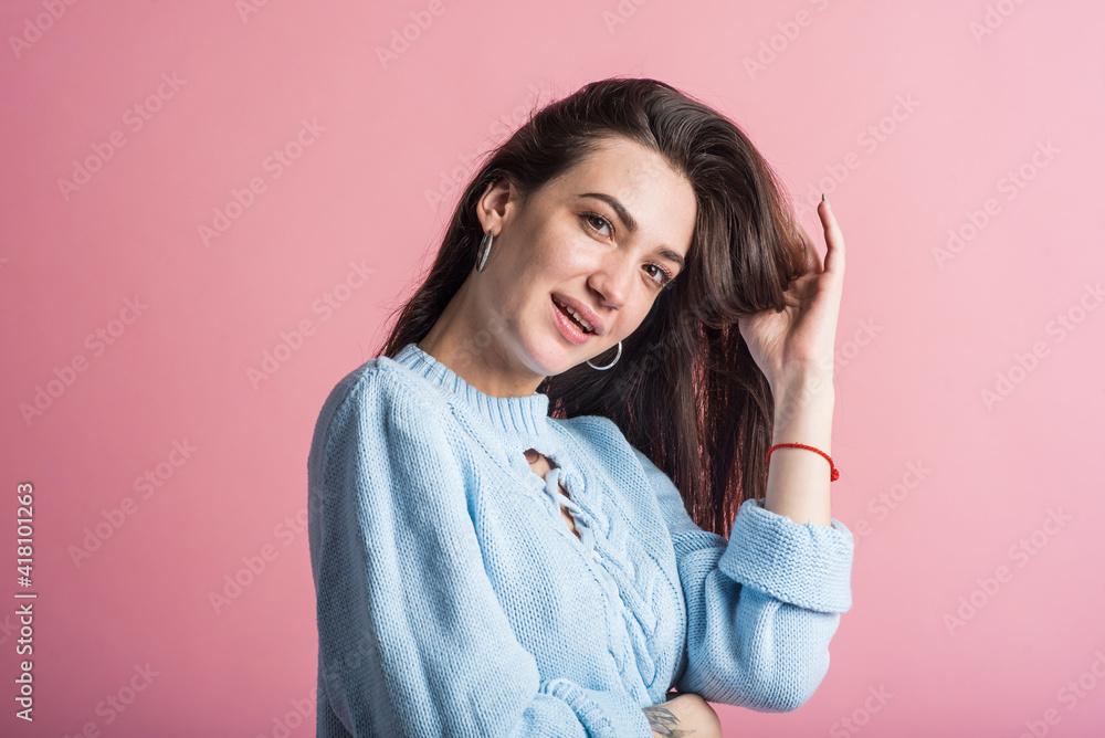 Portrait of a brunette girl on a pink background who is happy and smiling