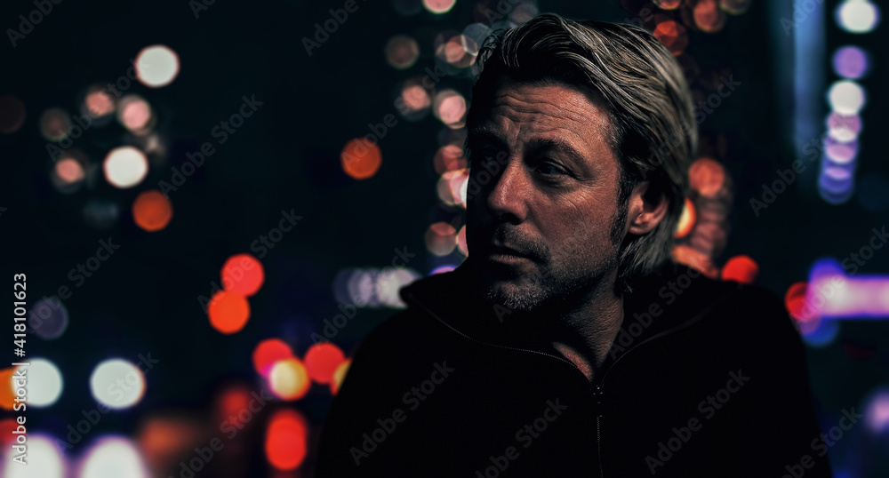 Rugged blond man with stubble beard on city street at night. Side view. Rugged blond man with stubble beard on city street at night. Side view.