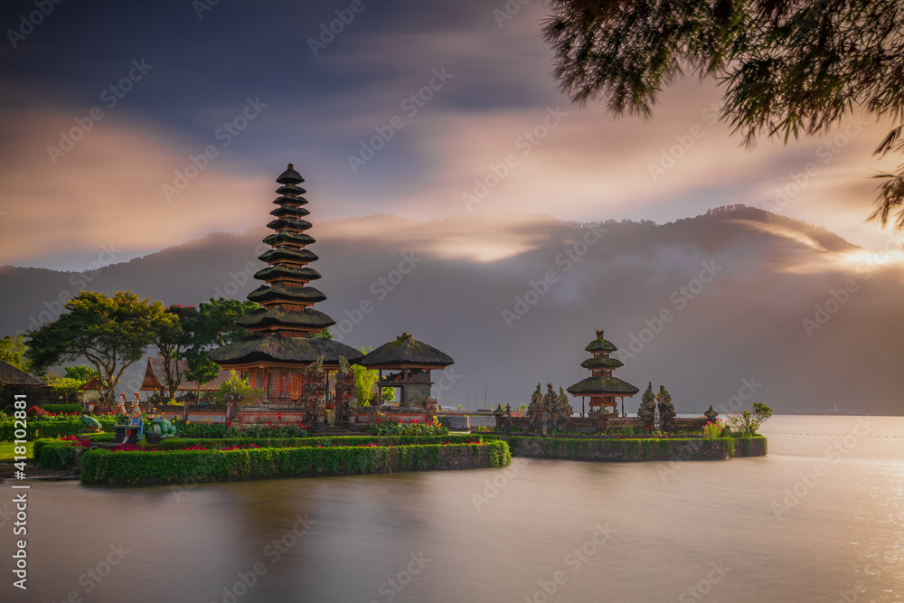 Pura Ulun Danu Bratan temple in Bali island. Beautiful balinese temple. Balinese landmark. Cloudy sky. Water reflection. Foreground with bamboo branches. Bratan lake, Bedugul, Bali