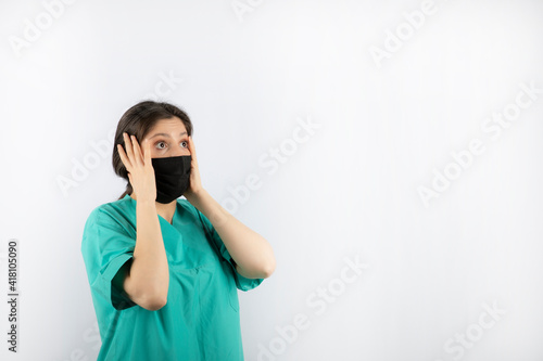 Shocked young nurse holding her hand to her head and looking away