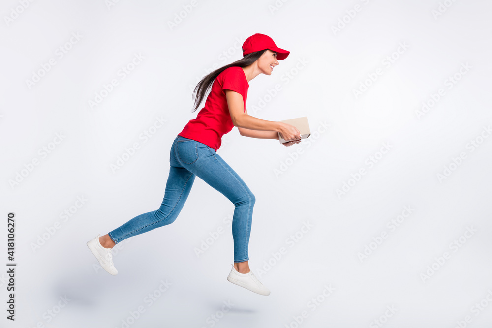 Full size profile side photo of young happy excited delivery girl running with parcel in hands isolated on grey color background