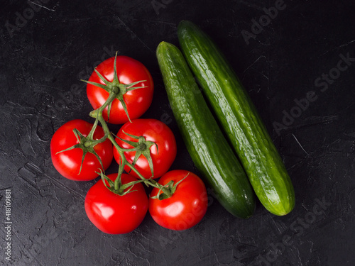Red tomatoes and cucumber on a black background. Studio photo
