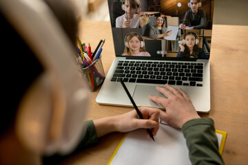 Little boy studying by group video call, use video conference with teacher, listening to online course. Using stationery, notebook. Easy, comfortable usage concept, education, online, childhood.