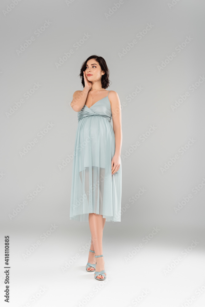 Stylish pregnant woman standing on grey background Stylish pregnant woman standing on grey background