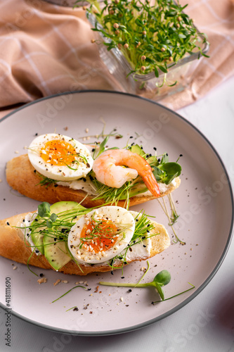 Breakfast with bruschetta with shrimps, eggs and microgreens in a plate