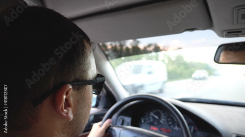 Unrecognizable man in sunglasses driving car on highway. Young confident guy looking to road during controlling auto. Back view from vehicle salon. Concept of road trip. Slow motion © olehslepchenko