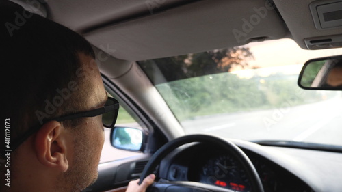 Unrecognizable man in sunglasses driving car on highway. Young confident guy looking to road during controlling auto. Back view from vehicle salon. Concept of road trip. Slow motion © olehslepchenko