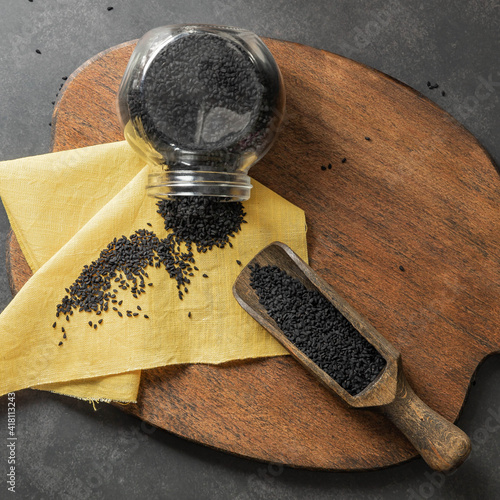 Black kumin seeds on a wooden cutting board ans wooden spoon.   photo