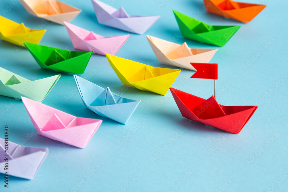 Red leader paper ship leading among others on blue background. Leadership concept. Red leader paper ship leading among others on blue background. Leadership concept.