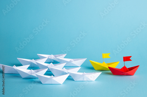 Fototapeta Naklejka Na Ścianę i Meble -  Red leader paper ship leading among others on blue background. Leadership concept.