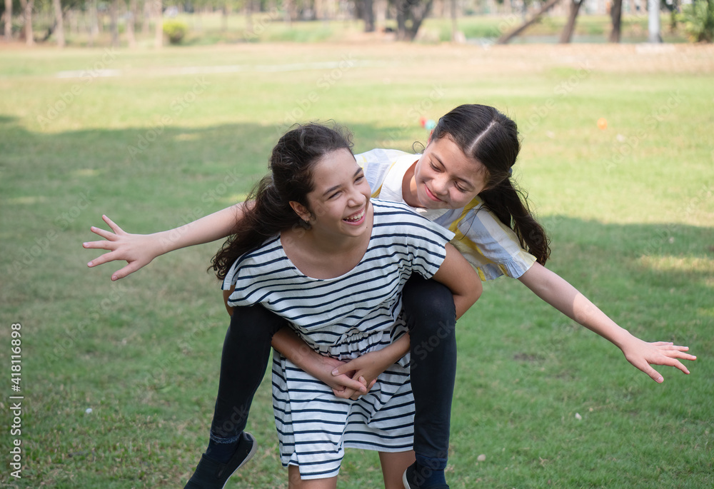 Two lovely young girls cheerfully spend time in the park. Girlfriends enjoy nature and communication.. Two lovely young girls cheerfully spend time in the park. Girlfriends enjoy nature and communication..