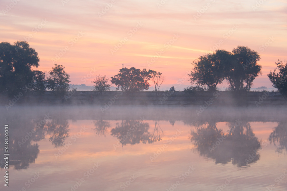 Pink foggy dawn on the  misty lake