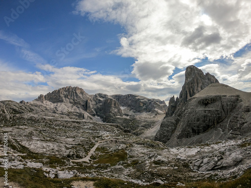 A distant view on a high and desolated mountain peaks in Italian Dolomites. The lower parts of the mountains are overgrown with moss and grass. Raw and unspoiled landscape. A bit of overcast. photo