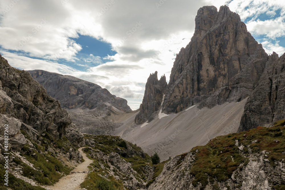 Obraz premium A panoramic view on Italian Dolomites. There are many high and sharp peak in front, with many landslides. Dangerous climbing. Barely any plants growing in the area. Raw and unspoiled landscape.