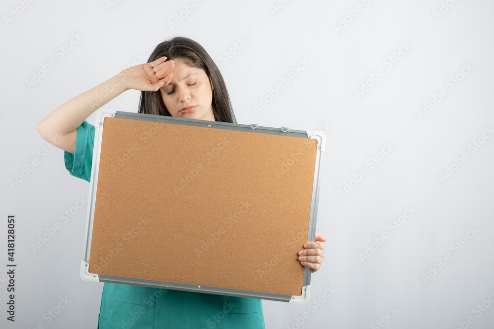 Tired young medical worker holding board with hand Tired young medical worker holding board with hand