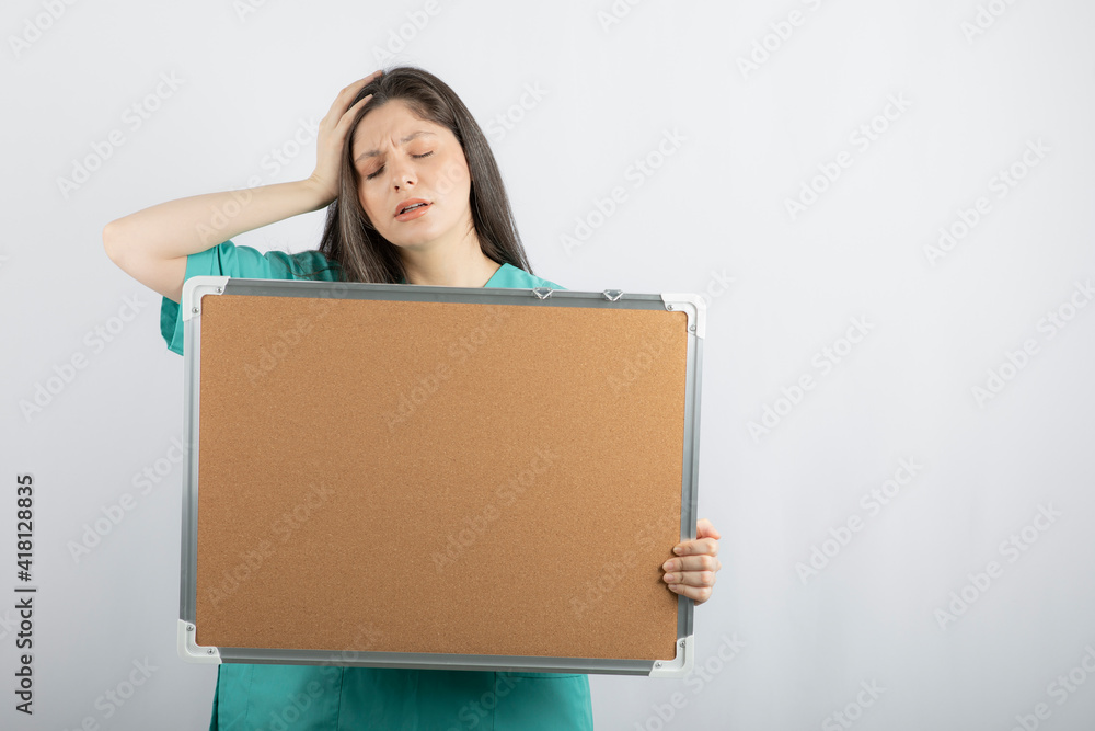 Tired young nurse holding board with hand Tired young nurse holding board with hand
