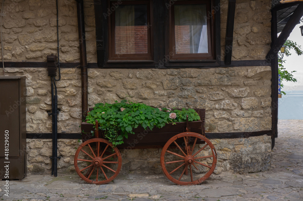 Wall of an old house with a fake wagon in which ivy grows