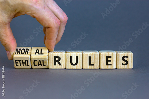 Ethical or moral rules symbol. Businessman turns wooden cubes and changes words 'ethical rules' to 'moral rules' on a beautiful grey background. Business, ethical or moral rules concept. Copy space. photo