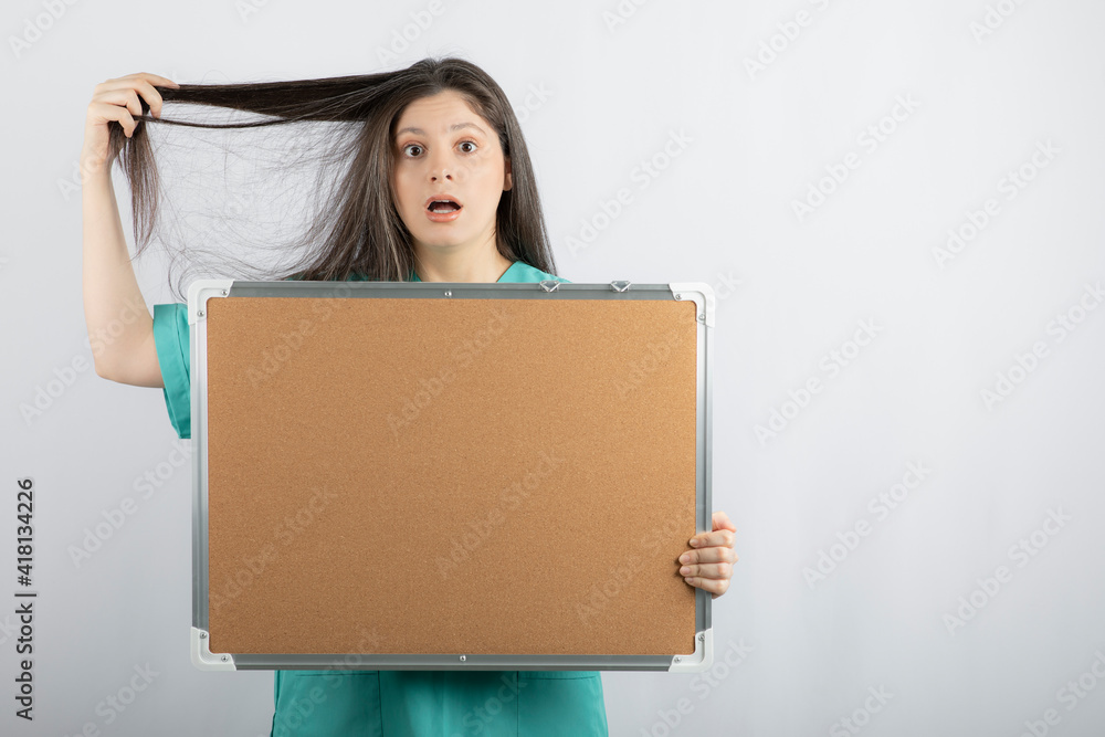 Shocked medical worker holding board and stretching her hair Shocked medical worker holding board and stretching her hair
