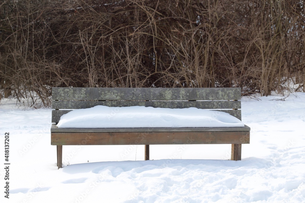 A close view on the snow covered park bench in the park.