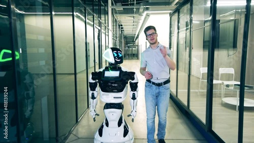 Human and robot communication concept. Businessman is chatting to a robot in the office space photo