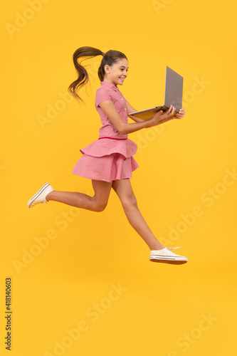 It is bargain. child jump with computer. happy kid play game on notebook. just have fun. © Olena