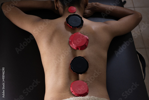 Brunette woman lying on a therapeutic stretcher with biomagnetism therapy magnets placed on her spine to treat her health with holistic therapies and alternative medicine