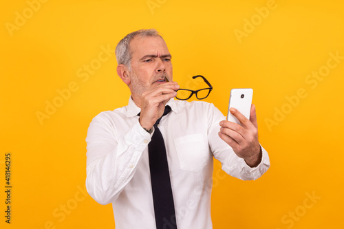 isolated senior adult man with presbyopia or eyestrain looking at phone photo