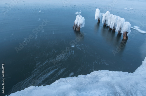 Ice breakwaters, covered with snow, stand in the winter sea. sea winter landscape background.